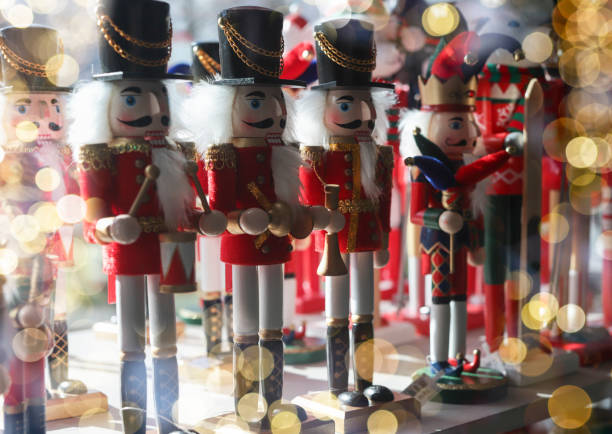 Nutcracker toys row on store shelf with blurred Christmas lights.