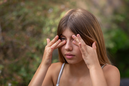 Young woman with allergy or cold symptoms rubbing her eyes