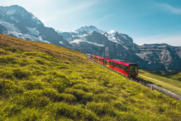 Photo of Electric modern tourist train and snowy mountains in background, Switzerland