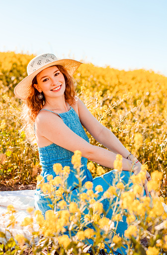 Girl in a yellow flower field sitting on a blanket