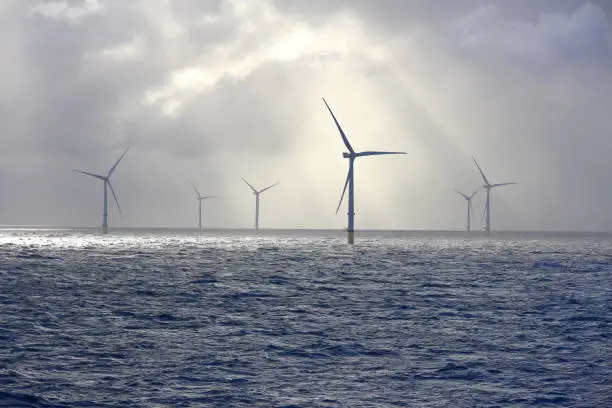 A beautifully lit scene with sunbeams on an offshore wind farm turbine.