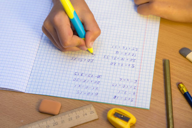 istock Close-up pupil's hand writes with a ballpoint pen in a notebook. 1350384955