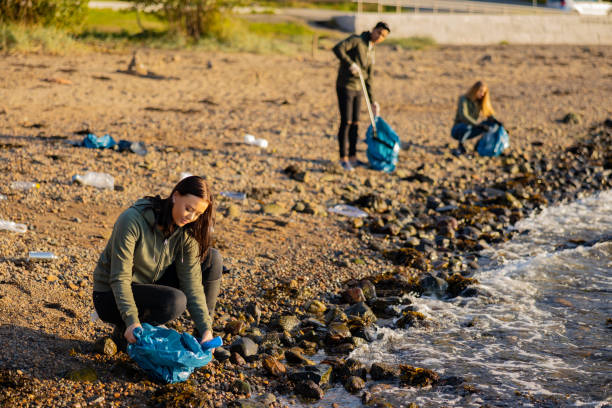 istock Dedicated woman in a team picking up garbage in bag at beach 1350386568