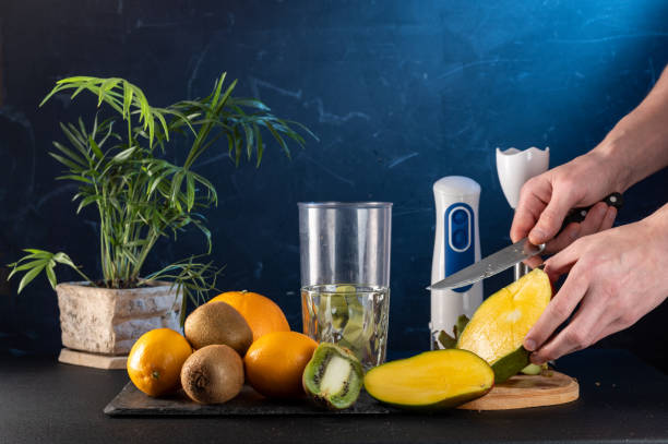 istock Peel the mango with a knife. Cut the mango into wedges. Knife and mango in hand. Fruit and mango cocktail. 1350391317