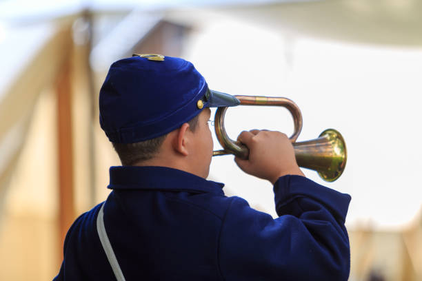 Excited young musician playing trumpet isolated on white background, rear view