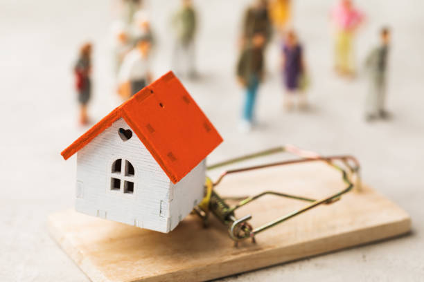A toy house in a mousetrap on the background of people, a concept on the topic of real estate fraud stock photo