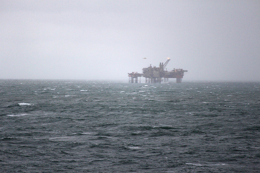 A remote oil rig with helicopter in shot, hazy atmospheric scene.