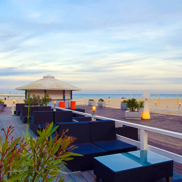 istock An atmospheric place on the beach. Empty tables and sofas on a wooden landing. 1350407673