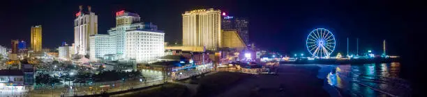 Photo of Panoramic aerial view of the Broadwalk on the waterfront in Atlantic City Downtown, the famous gambling center of the East Coast USA, with multiple casinos and amusing park with a Ferris Wheel on a pier.