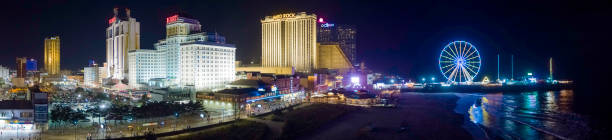 panoramic aerial view of the broadwalk on the waterfront in atlantic city downtown, the famous gambling center of the east coast usa, with multiple casinos and amusing park with a ferris wheel on a pier. - atlantic city gambling new jersey built structure imagens e fotografias de stock