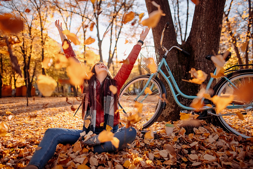 Woman throwing autumn leaves in the air