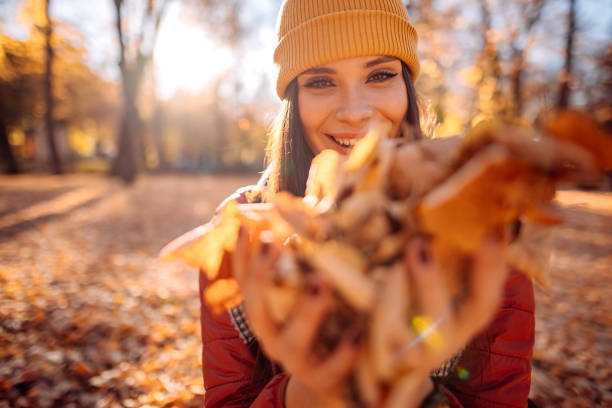 joven despreocupada divirtiéndose en un parque de otoño - autumn women leaf scarf fotografías e imágenes de stock