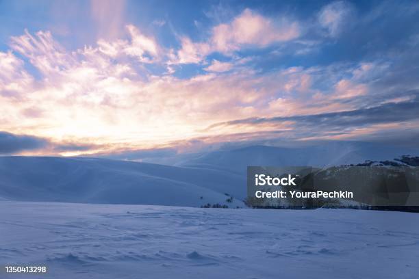 Fluffy Clouds Shelter Under White Snow Sheltered By Forests And Beautiful Mountains Stock Photo - Download Image Now