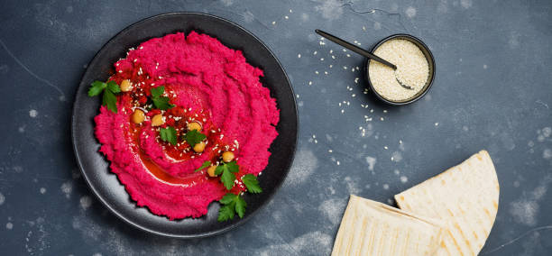 istock Homemade beetroot hummus in black ceramic dish on old dark concrete background. Selective focus. Top view. 1350415740