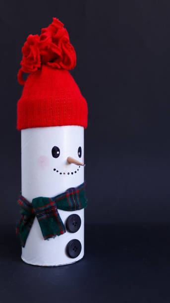 istock Handmade cardboard snowman, with red hat on black background 1350416843