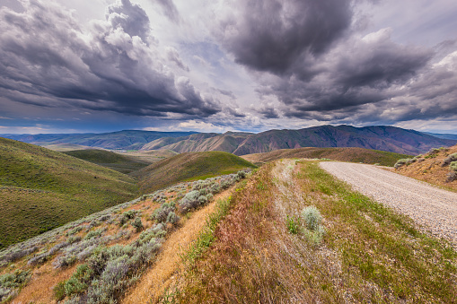 istock Dark sky over green hills. Colorful road in the mountains. Storm clouds and thunder sky. Oregon, Baker County, Lookout Mountain rd 1350417113