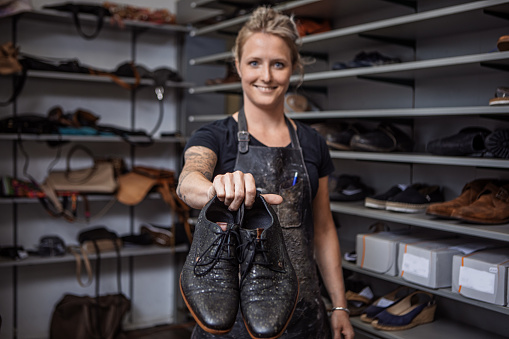 Beautiful blonde Female cobbler working in a shoemaker store after reopening in the new normal