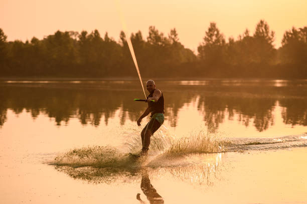 istock Smiling athletic muscular man holds rope and riding wakeboard 1350417706