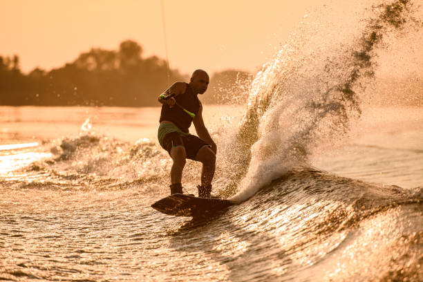 istock Great view of splashing wave and athletic man energetically riding wakeboard. 1350418405