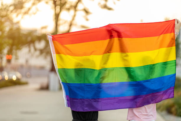 istock Portrait of happy non binary couple waving rainbow flag 1350420129