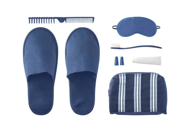 Flat lay of travel kit with slippers, cosmetic bag, eye mask and other accessories and toiletries