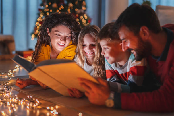 Parents and children reading fairytales while spending Christmas Eve together at home stock photo