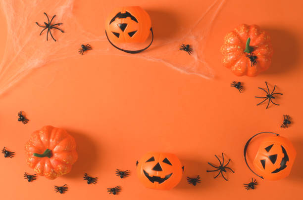 istock Pumpkins and spiders in a web on an orange background, top view, flat lay. Decorations for Halloween on an orange background, copy space. Halloween party. 1350424460