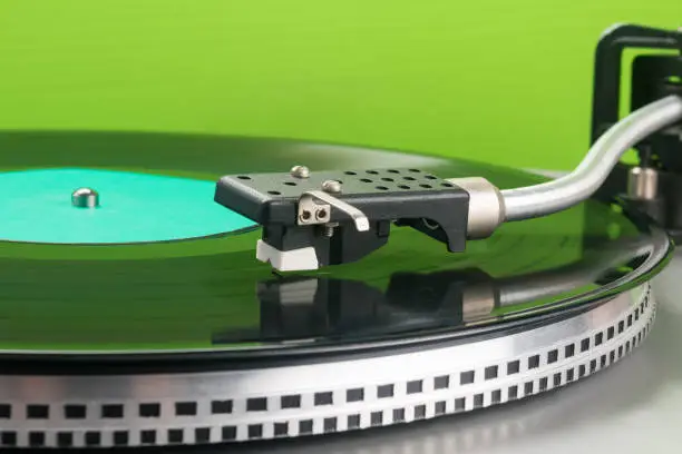 vinyl record player on green background, close-up