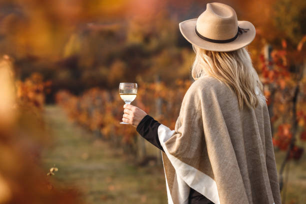 Female vintner enjoying white wine in autumn vineyard stock photo