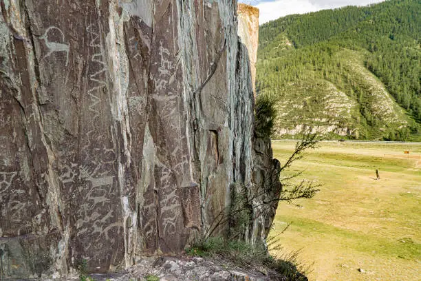 Photo of Rock carvings of ancient people in Kalbak-Tash, in the distance there is the Chuisky Deer stone Adyr-Kan or Olenny stone