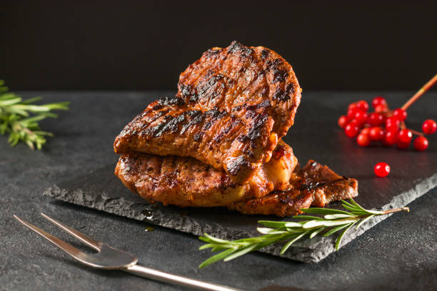 istock Meat steak with rosemary grilled on a black stone board. Side view 1350426101