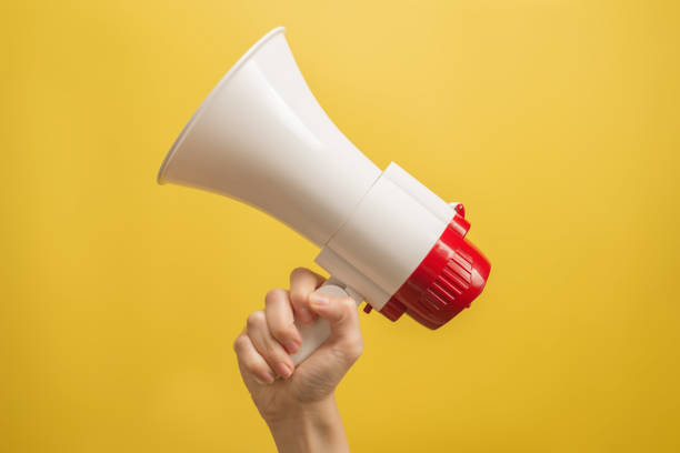 istock Megaphone in woman hands on a yellow background. 1350428546