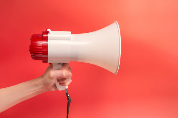 istock Megaphone in woman hands on a red background. 1350428554
