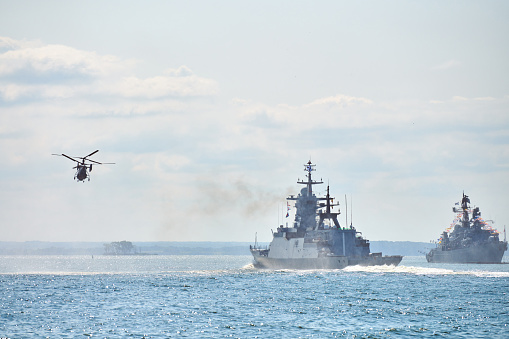 Battleships war ships corvette during naval exercises and helicopter maneuvering over water in Baltic Sea. Warships, helicopters and boats perform tasks in sea, military warships sailing, Russian Navy