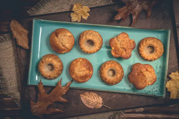 Homemade delicious mini bundt cakes, guglhupf, muffins on a blue plate on rustic wooden background, top view