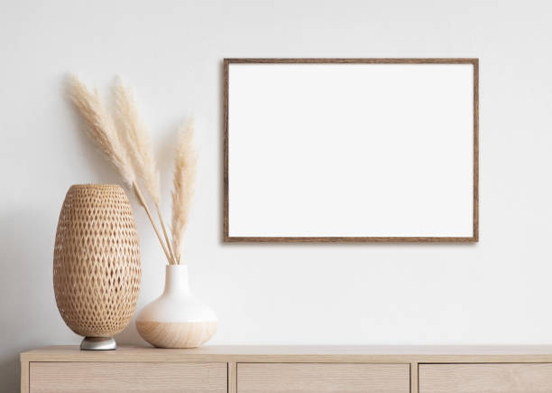 Artwork mock-up in interior design. Blank white picture frame on a white wall View of modern interior design. Minimalism concept, boho style. Blank white empty copy space for painting or poster. horizontal stock pictures, royalty-free photos & images