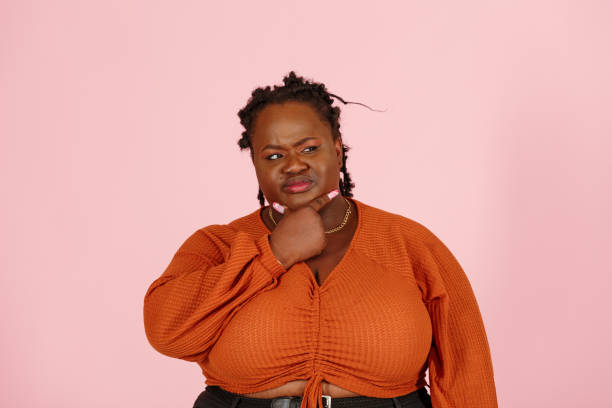istock Skeptical black plus size woman touches chin on pink background 1350433555