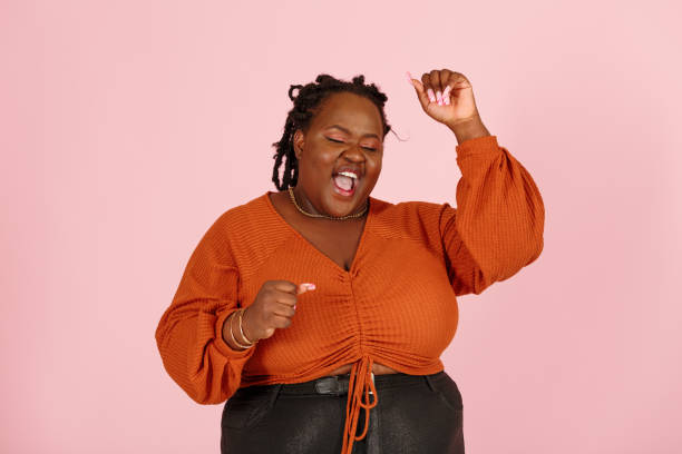 Excited black plus size woman happy of big win on pink background stock photo