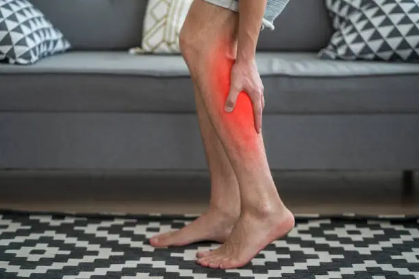 Photo of The man's calf muscle cramped, massage of male leg at home