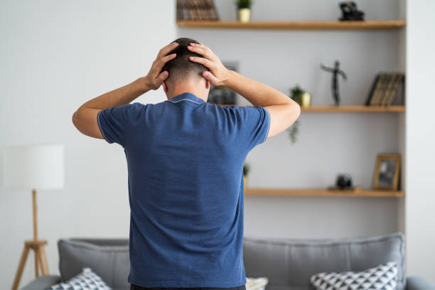 Headache and migraine, man with head pain in home interior stock photo
