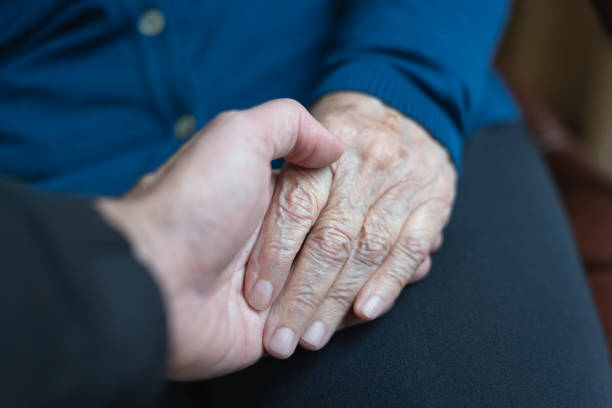 istock Young man's hand holding older woman's hand in caring and helping attitude. 1350444610