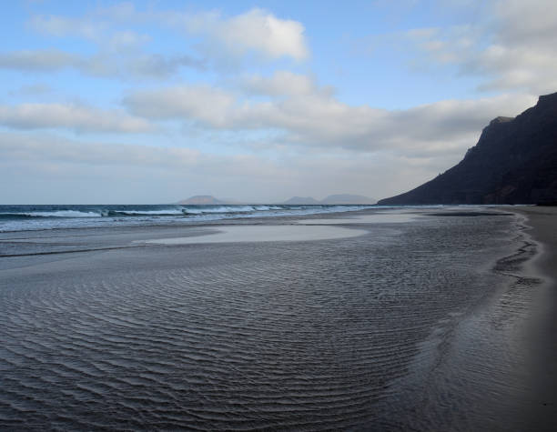Beach at low tide, Famara, Lanzarote, Spain Large sandy beach at low tide, coast of Famara, Lanzarote Island, Spain caleta de famara lanzarote stock pictures, royalty-free photos & images