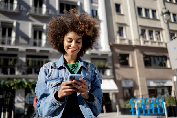 istock Happy young mixed race woman using a smart phone outdoors 1350454885