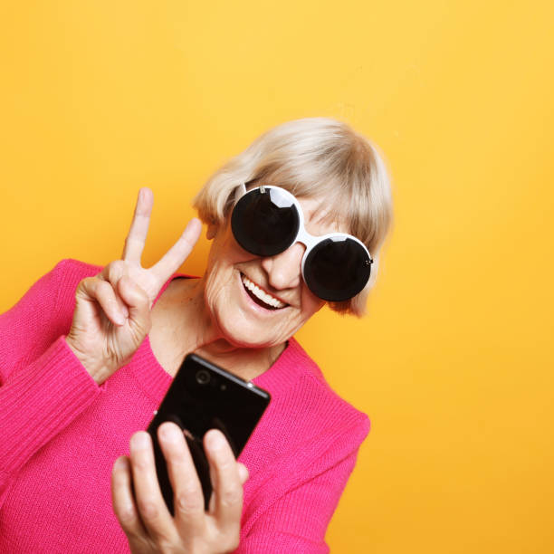 istock Elderly lady holding a smartphone and making v-sign 1350457969
