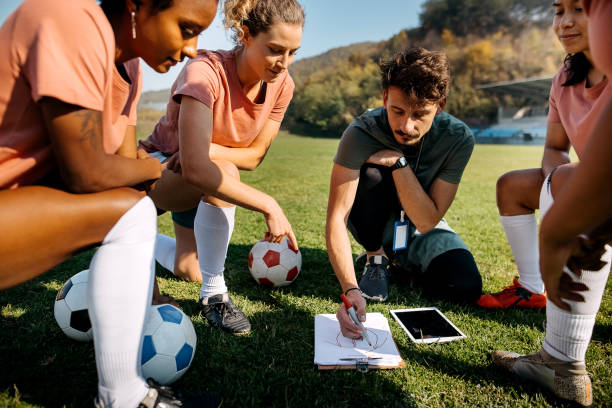 istock Girls soccer team talking to coach on training 1350457992