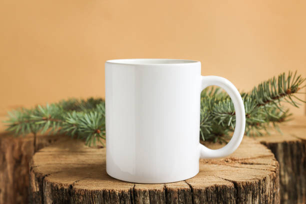 istock White mug on a wooden stand with fir branches front view. Mockup for print, copy space and advertising. 1350463632