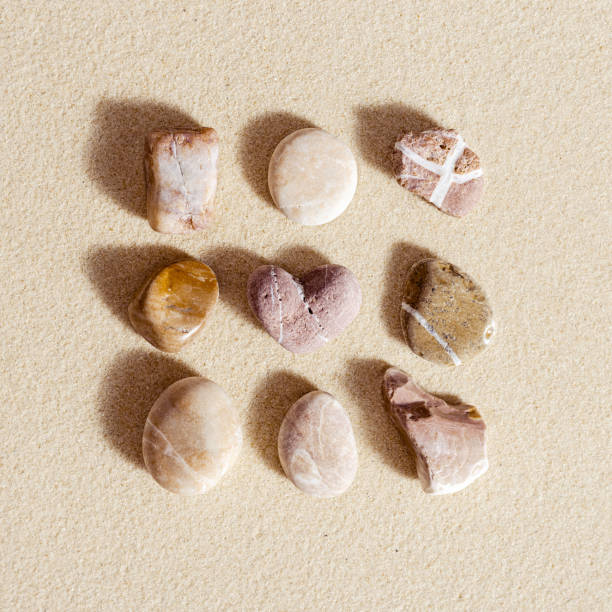 istock Sea stones neutral colors on natural fine sand background. Summer square composition from natural pebbles and one stone heart 1350464897