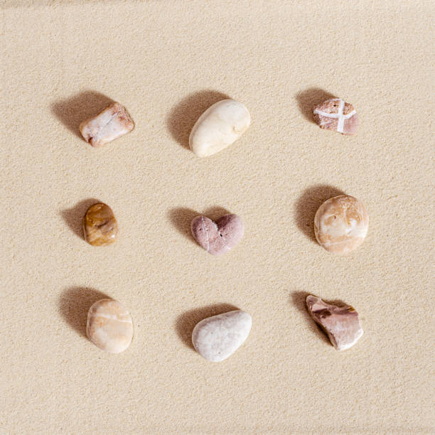 istock Aesthetic minimal pattern with set of pebble stones on fine sand background. Square composition from natural material with stone heart 1350464898
