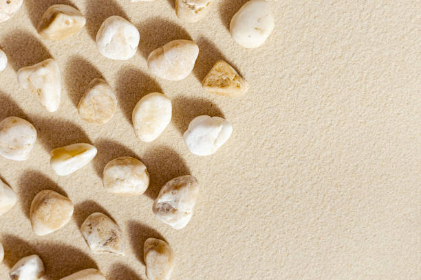 istock Pattern with close up pebble sea stones on sand texture. Layout from natural stone neutral tones. Minimal style sandy background with copy space 1350464899