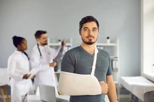 Photo of Portrait of caucasian man with bandage on broken hand standing in hospital ward